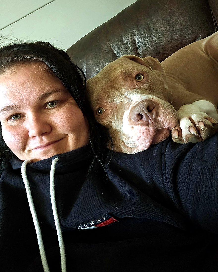 Chelsey relaxing at home with a dog snuggled contentedly on her shoulder